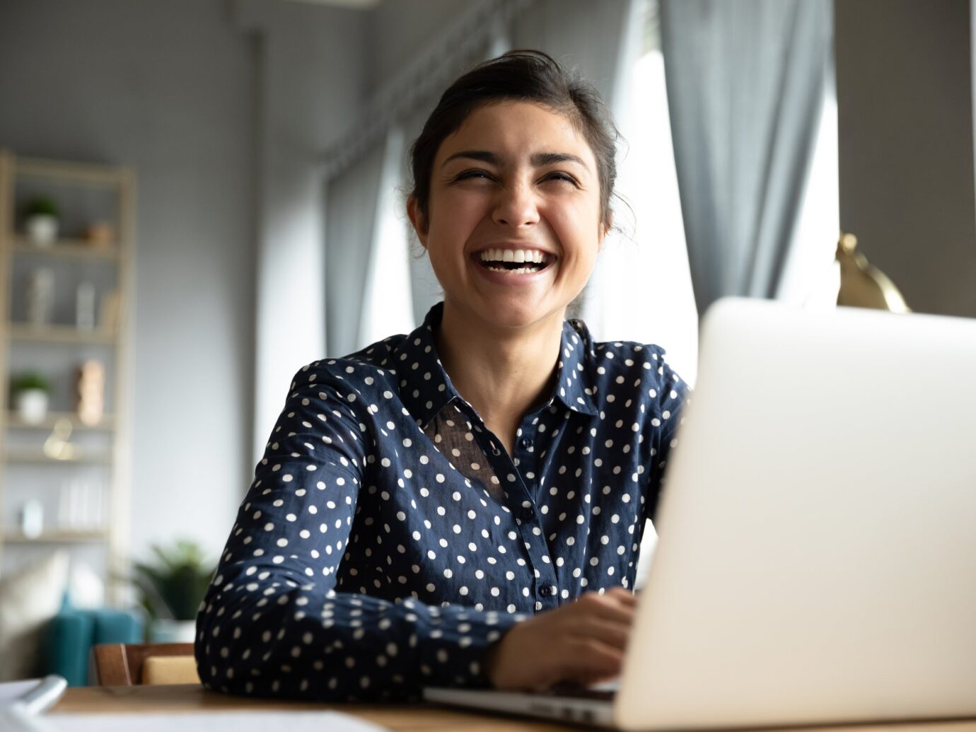 Woman at her laptop laughing