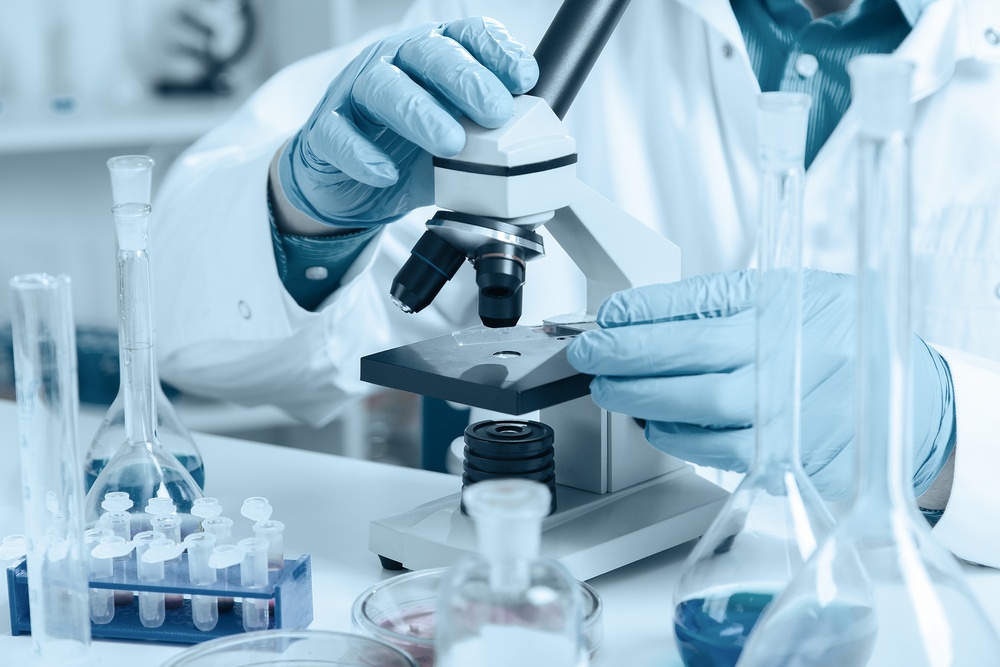Gloved hands adjusting a microscope